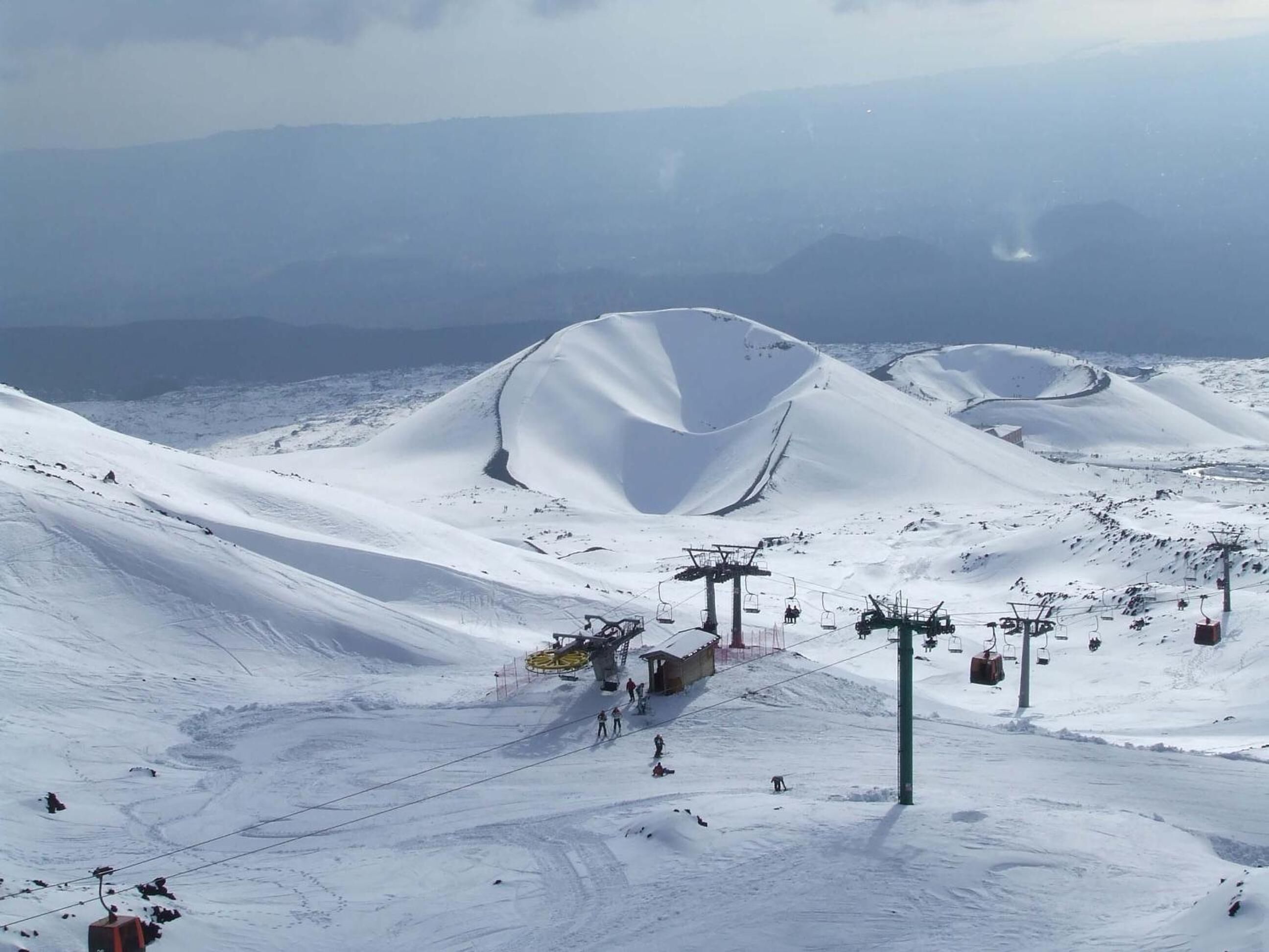 Pista da sci innevata con impianti di risalita e un piccolo chalet.