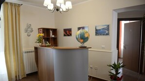 Un mostrador de recepción con un globo terráqueo, una estantería y una planta en maceta.