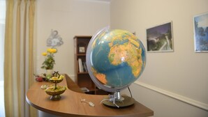 Un globo sobre una mesa de madera en una habitación con una estantería y un cuadro en la pared.