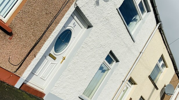 A white building with a door marked "83" and a window with a blue frame. - Charming Terrace (Larne)