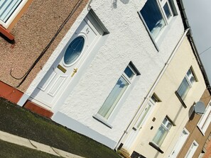 A white building with a door marked "83" and a window with a blue frame. - Charming Terrace (Larne)