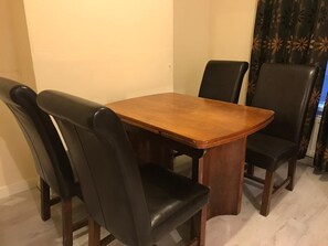 A dining table with four black leather chairs. - Charming Terrace (Larne)