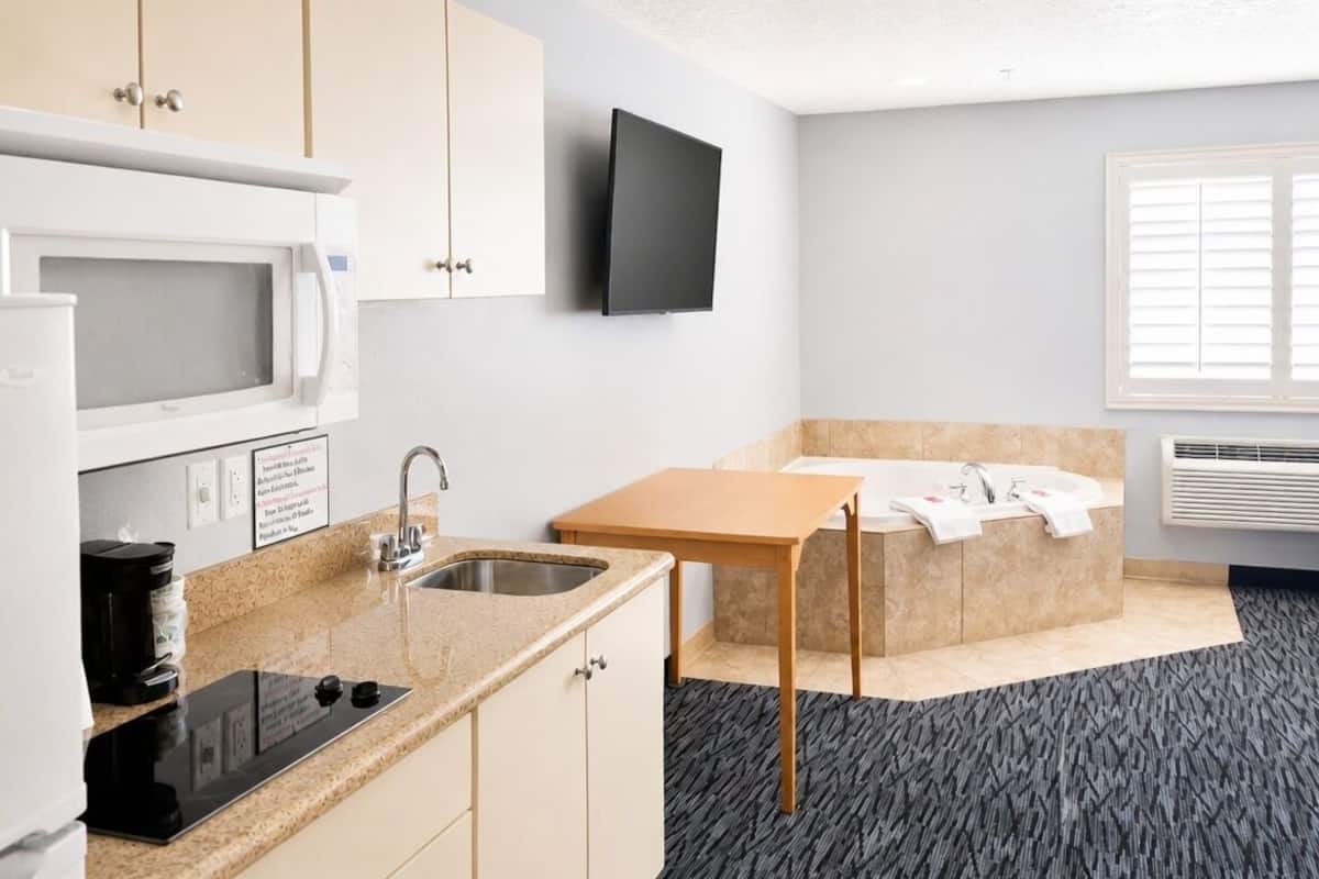 A compact kitchenette with a microwave, coffee maker, and sink.