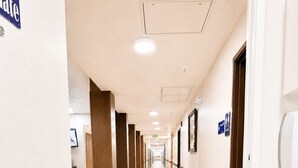 Een hotelgang met houten vloer, deuren aan de rechterkant en een zithoek aan de linkerkant.