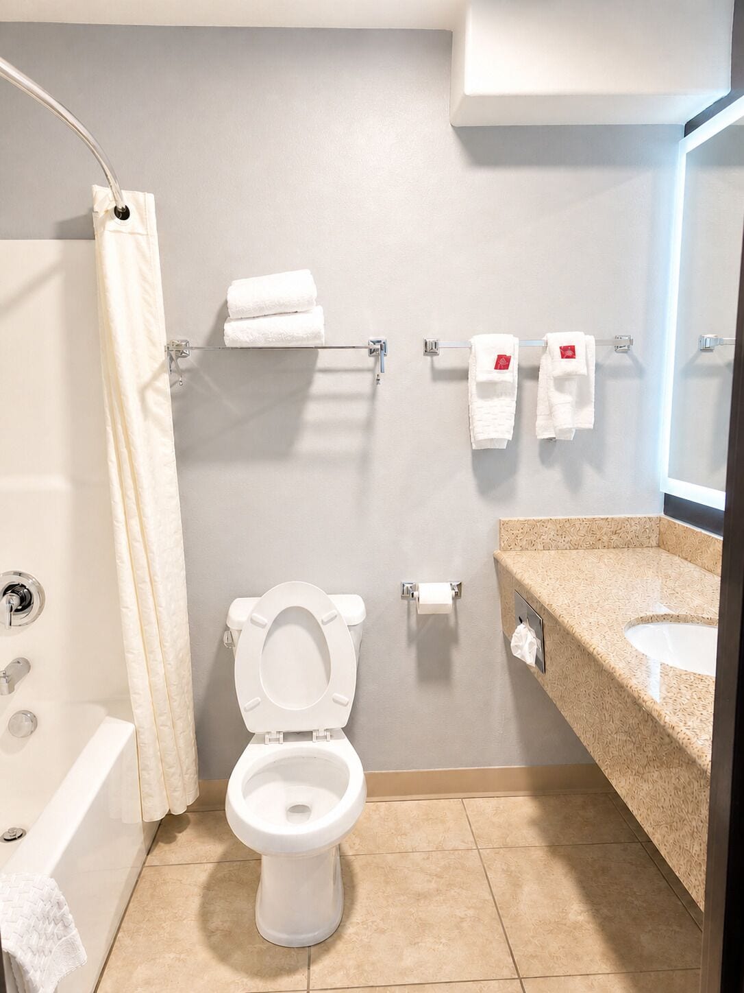 Uma casa de banho moderna com sanita, lavatório e chuveiro.