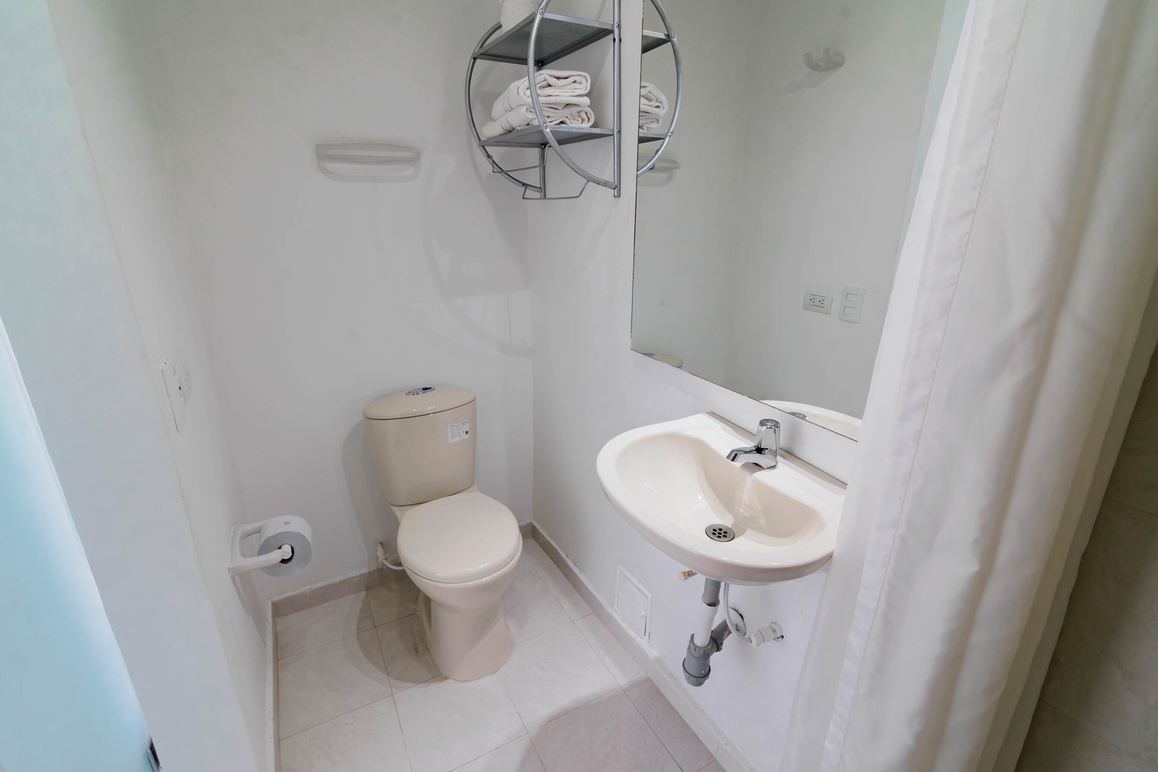 A small, clean bathroom with a toilet, sink, and a towel rack.