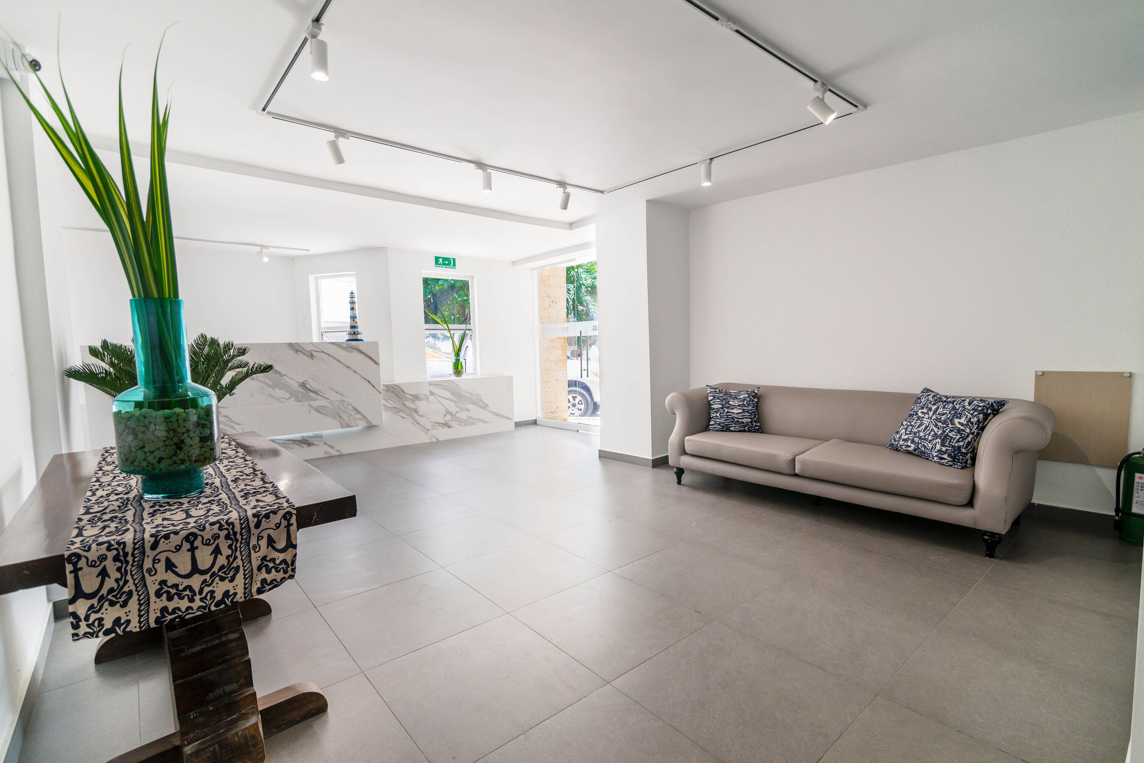 A spacious lobby with a marble reception desk, a beige sofa, and a potted plant.
