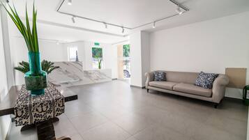 A spacious lobby with a marble reception desk, a beige sofa, and a potted plant.