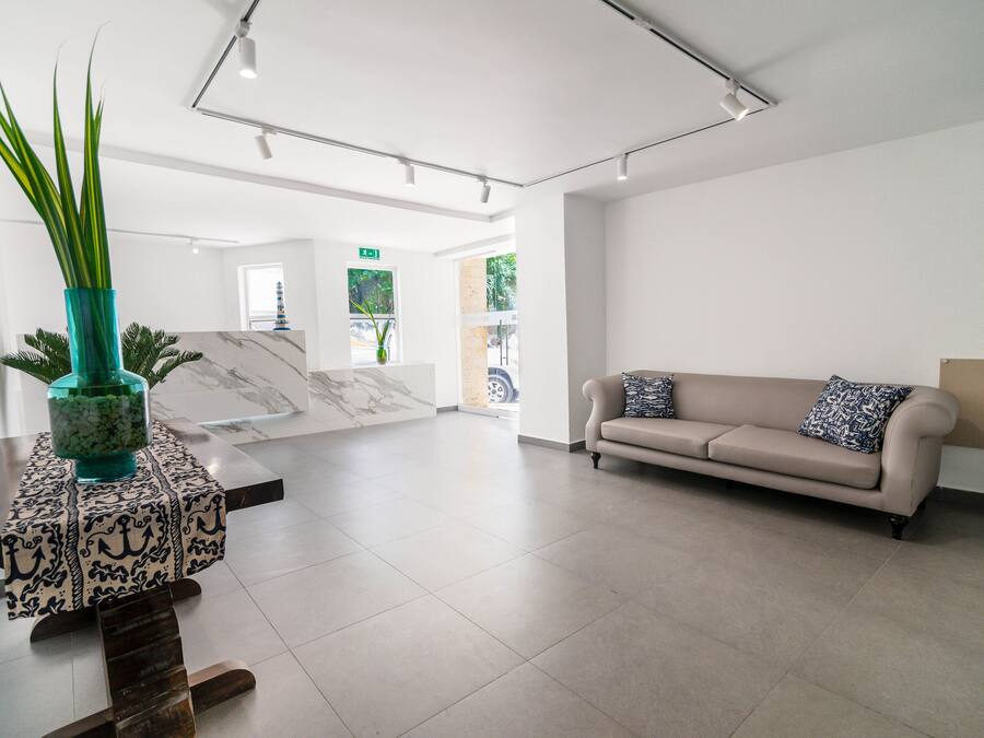 A spacious lobby with a marble reception desk, a beige sofa, and a potted plant.