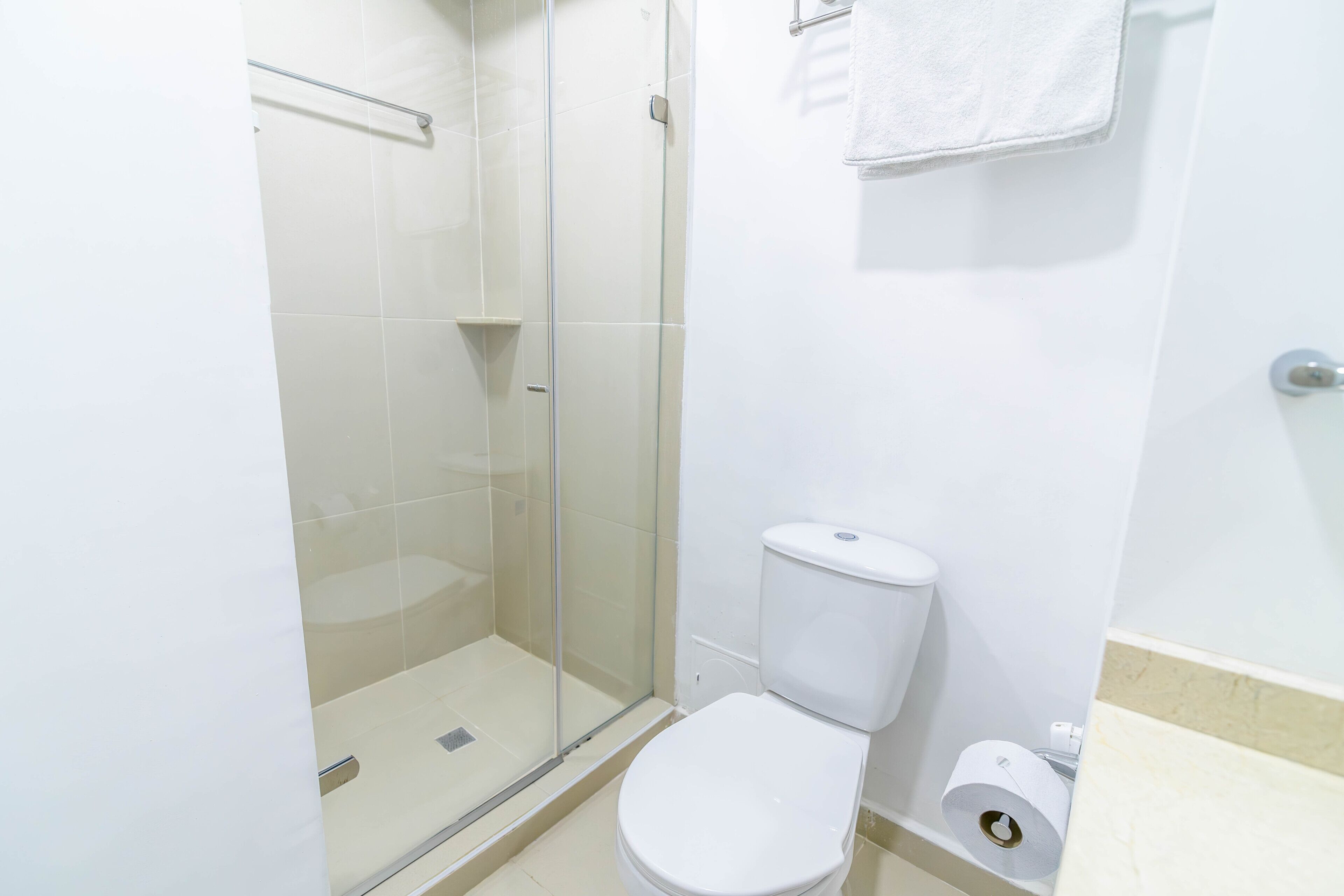 Een badkamer met een douche met glazen wand, een toilet en een handdoekhouder.
