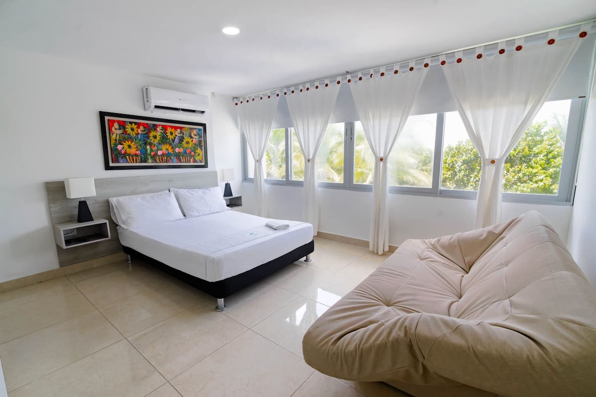 A modern bedroom with a bed, a bedside table, a chair, and a window with curtains.