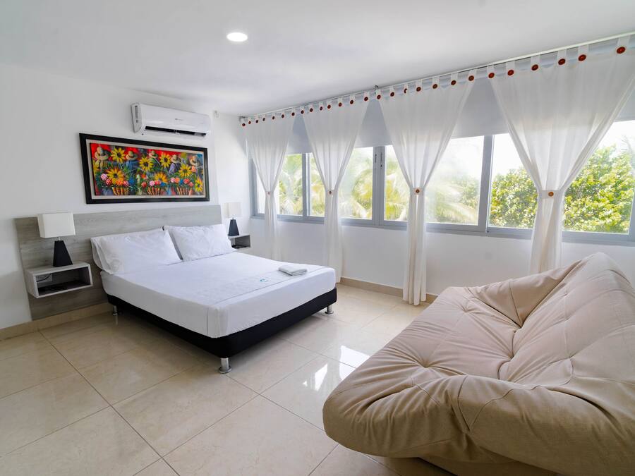 A modern bedroom with a bed, a bedside table, a chair, and a window with curtains.