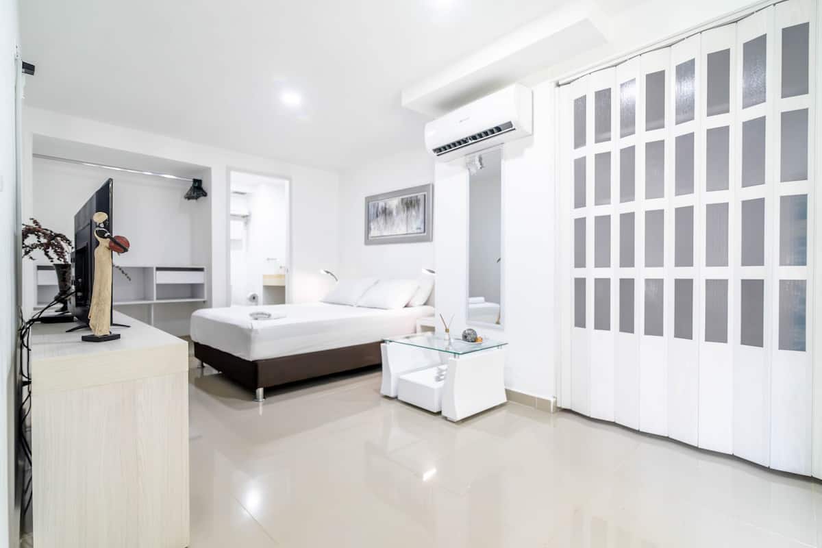 A modern bedroom with a bed, bedside table, and a large window.