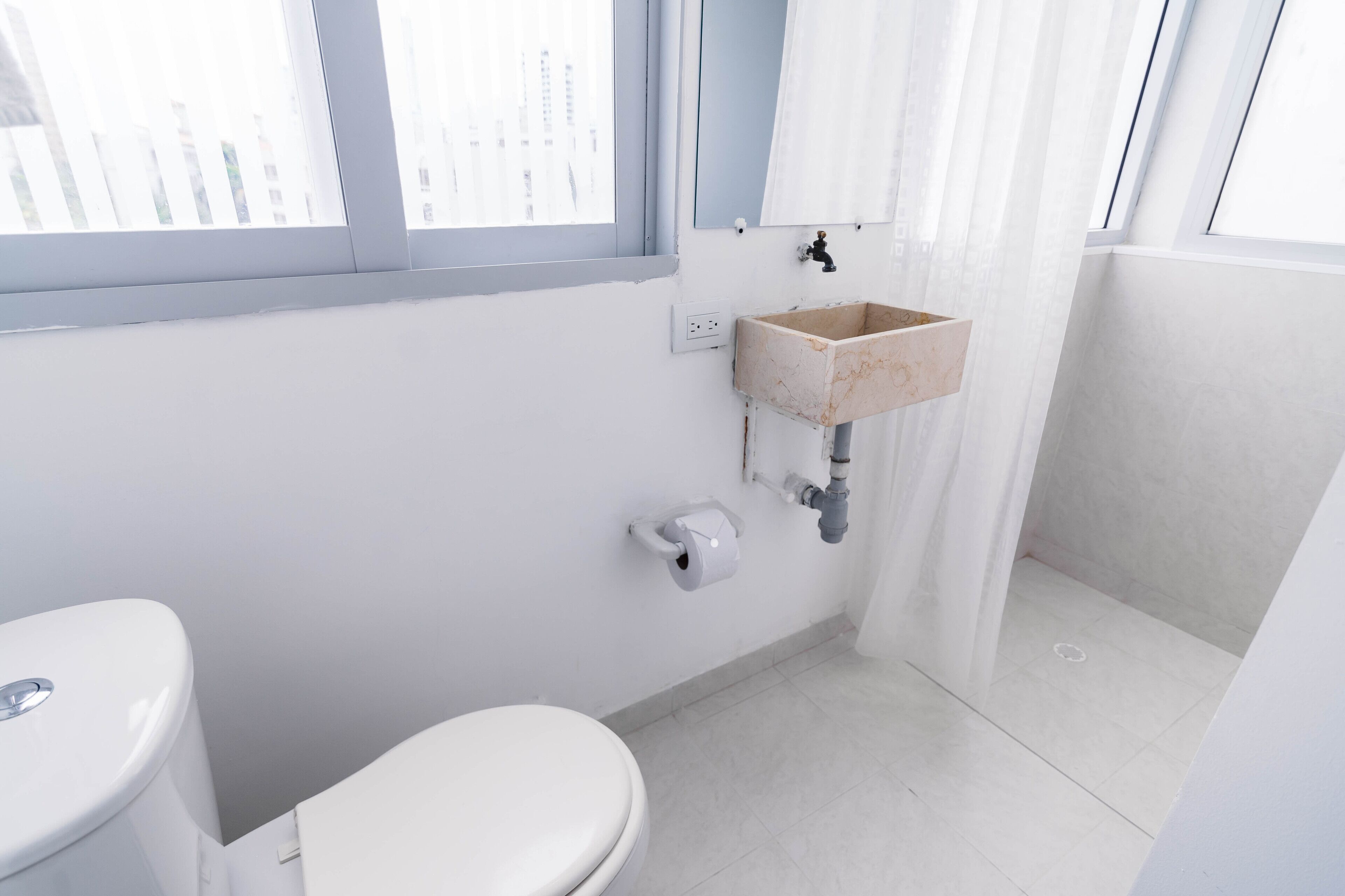 A small, modern bathroom with a toilet, a sink, and a window.