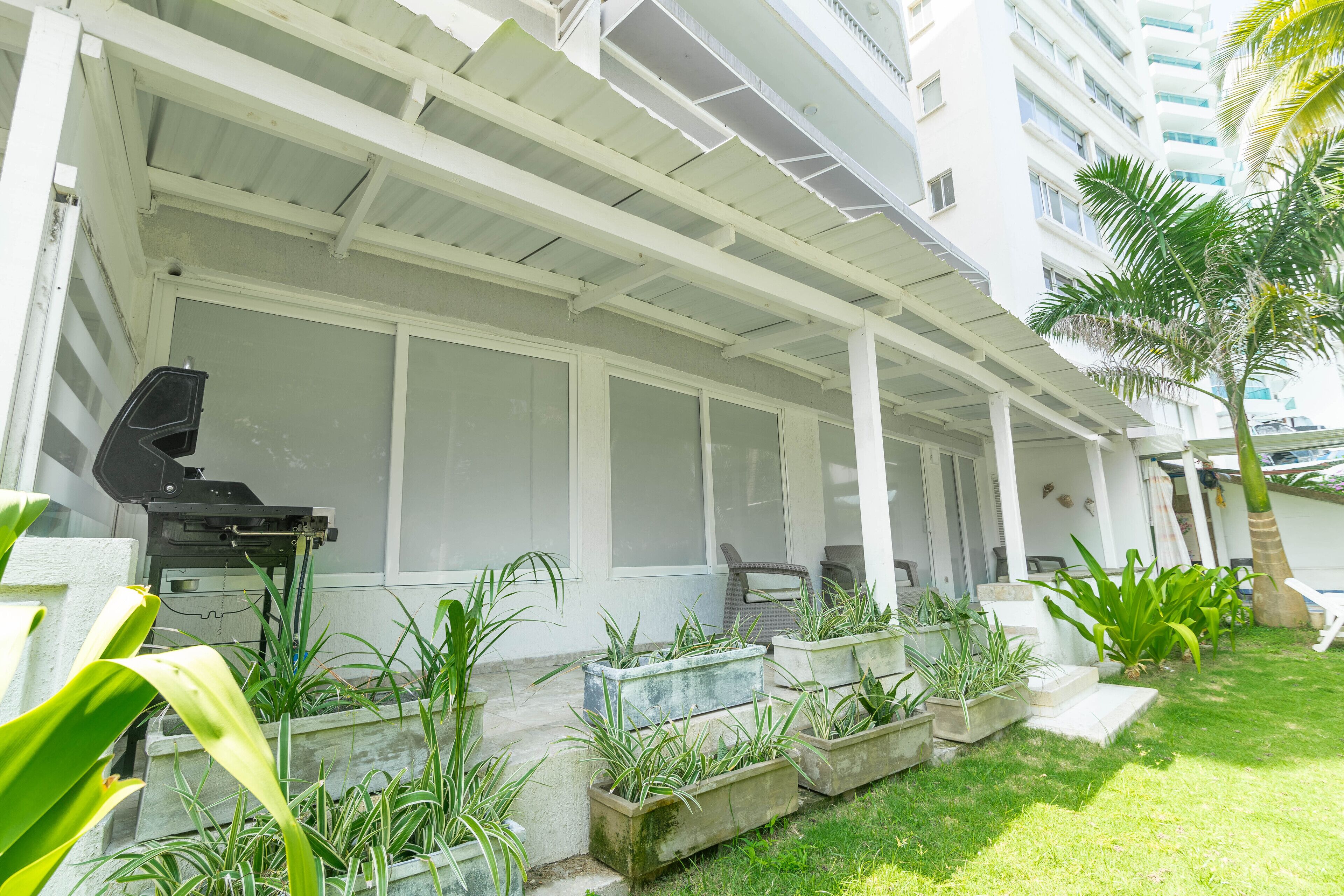 A covered outdoor area with planters and a grill.