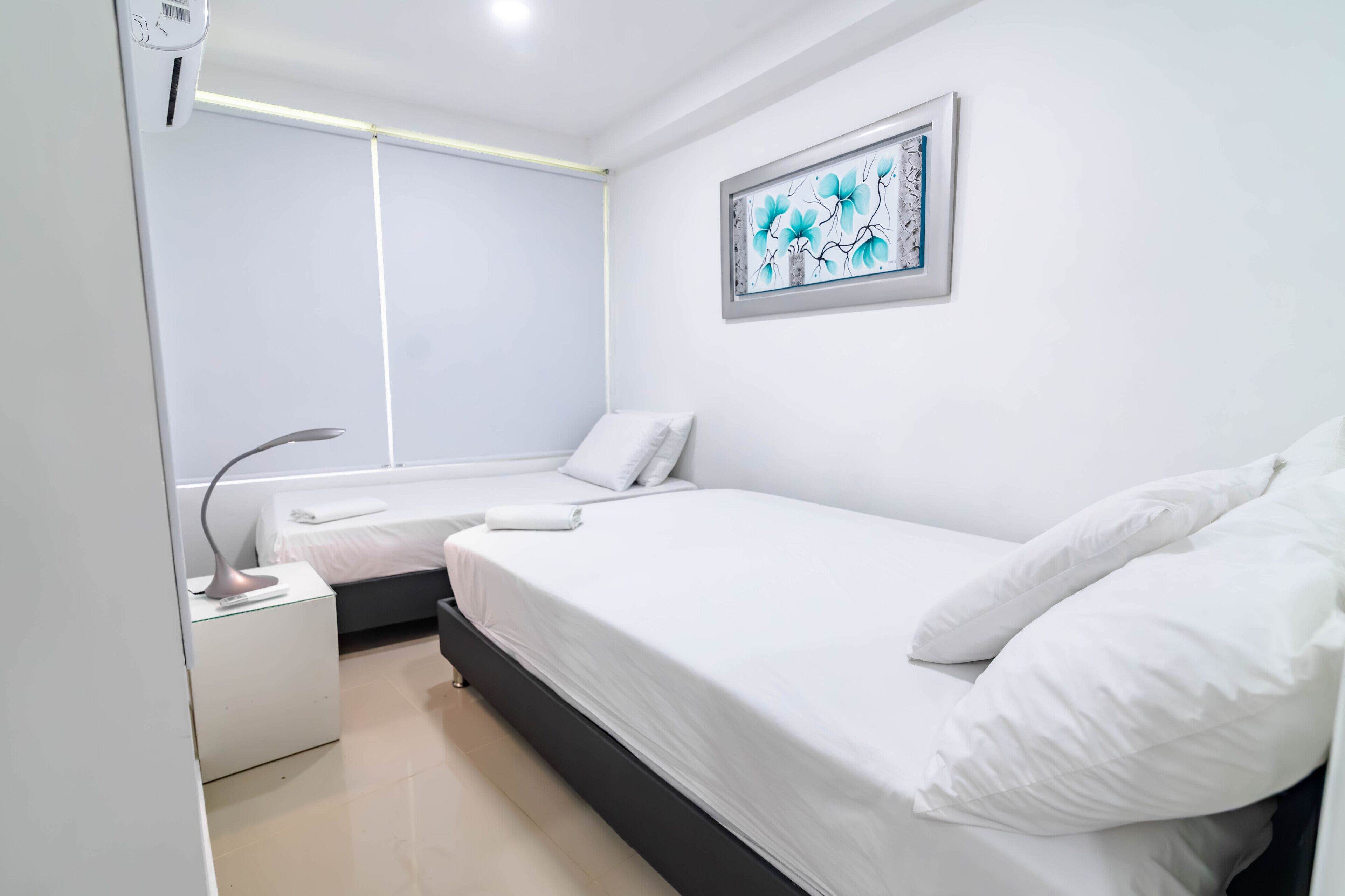 A modern bedroom with a bed, bedside table, and a wall-mounted artwork.