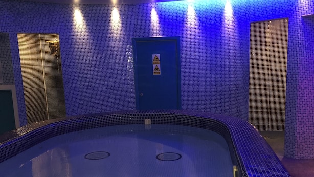 Ein großes Hallenbad mit blau gefliesten Böden und Wänden, umgeben von einer niedrigen Mauer.
