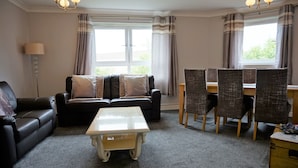 Ein Wohnzimmer mit einer Couch, einem Couchtisch, einem Esstisch mit Stühlen und einer Lampe.