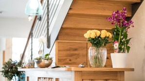 A wooden reception desk with a vase of yellow flowers and a potted plant. - Stefanies Cafe Pension Culture (Bad Feilnbach)