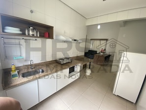 Eine moderne Küche mit weißen Schränken, einer Arbeitsplatte aus Granit, einem eingebauten Herd und einem Kühlschrank.
