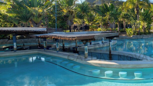Une piscine à l’eau cristalline, entourée d’une végétation tropicale et bordée d’un paysage rocheux.