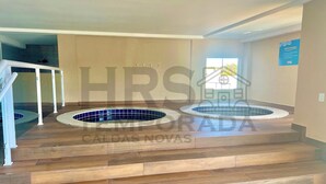 Un espace piscine comprenant deux bains à remous, un revêtement de sol en bois et un escalier menant à un niveau supérieur.