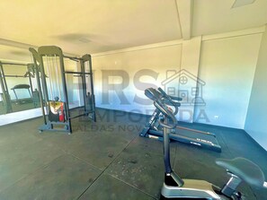Un gimnasio con equipo de ejercicio, incluyendo una cinta de correr, una máquina de pesas y una barra para dominadas.