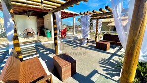 Un espace extérieur aménagé en terrasse, avec des pergolas en bambou, des meubles en osier et une vue sur le paysage environnant.