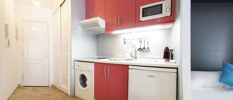 A compact kitchen with a microwave, sink, and washing machine.
