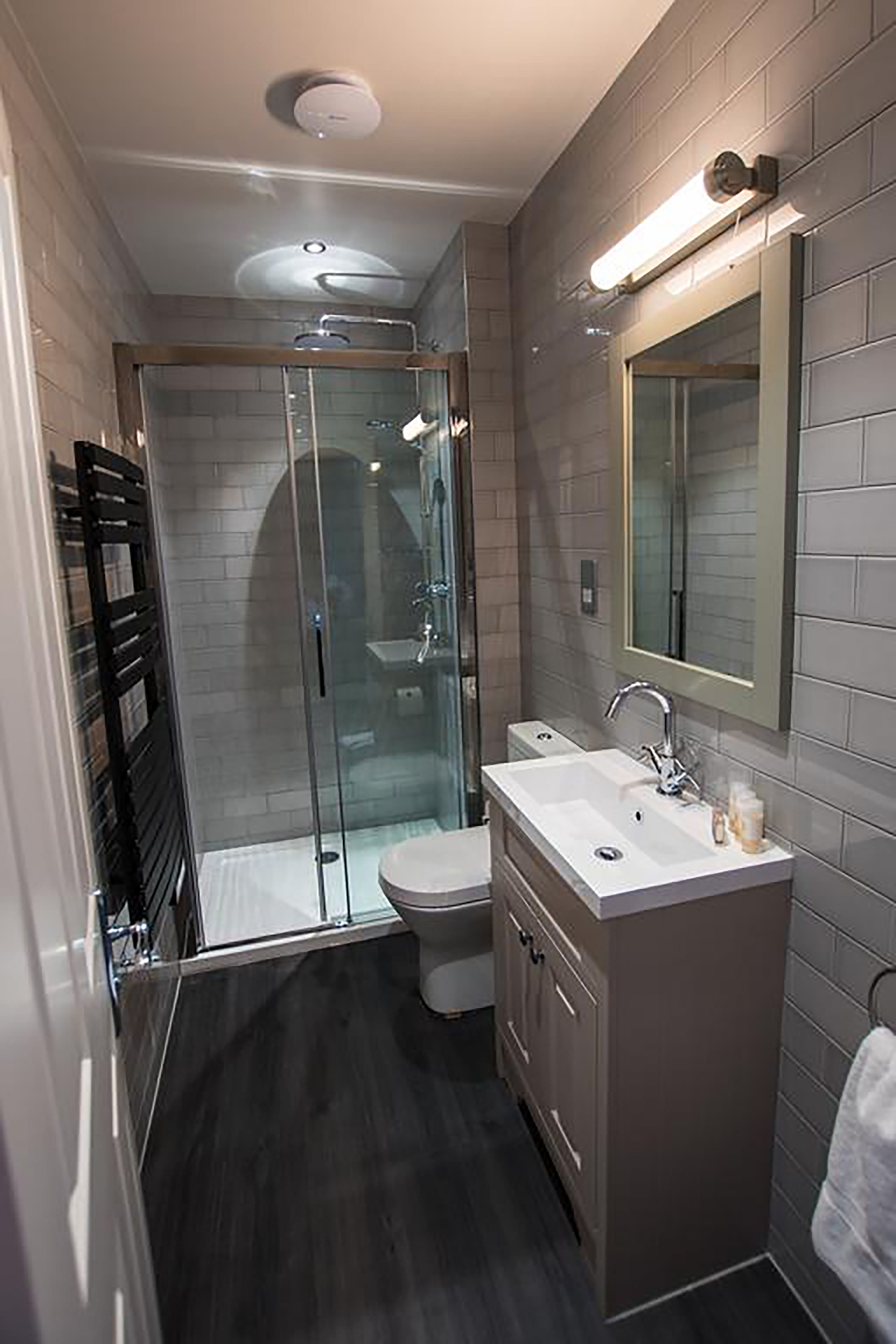 A modern bathroom with a glass-enclosed shower, a white sink, and a mirror above it.