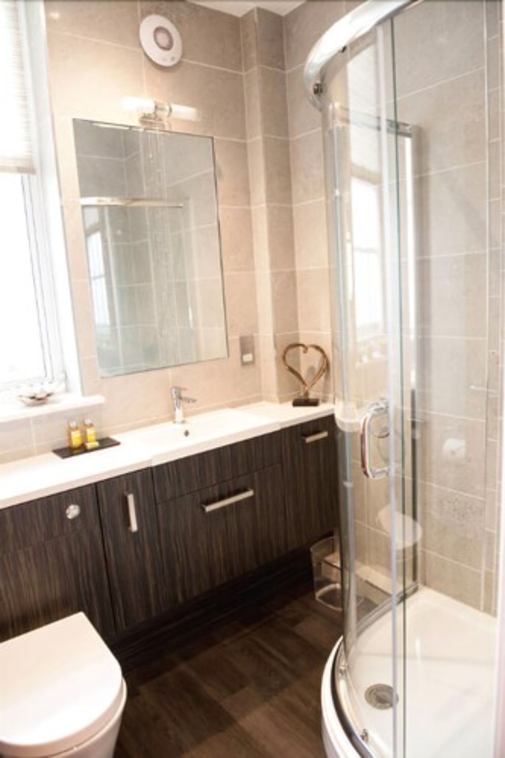 Une salle de bain moderne avec une douche à parois de verre, un meuble-lavabo avec un miroir et des toilettes.