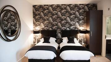 A double bed room with a mirrored wall, a patterned wallpaper, and a wardrobe.