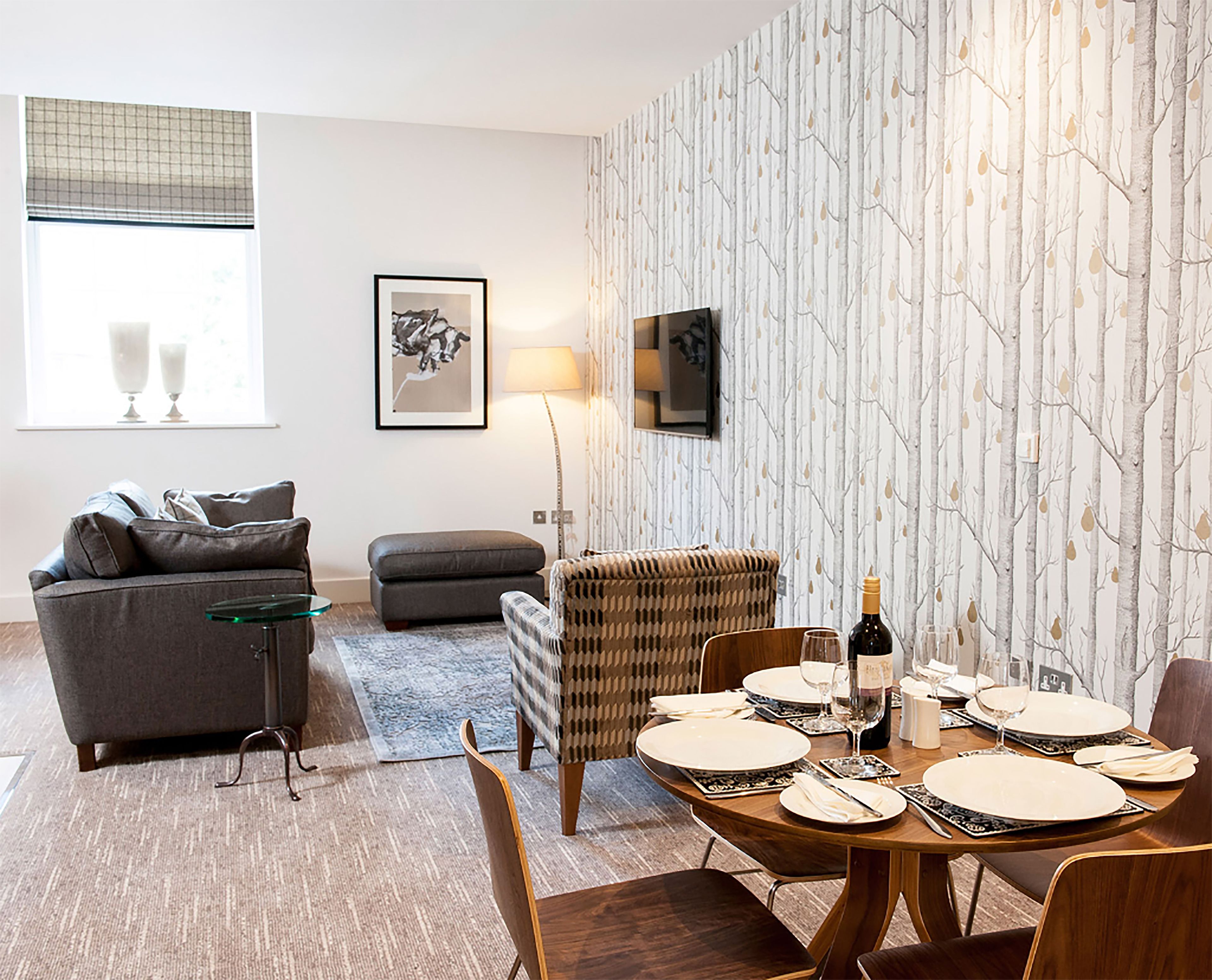 A modern living room with a dining area, a sofa, a coffee table, and a TV mounted on the wall.