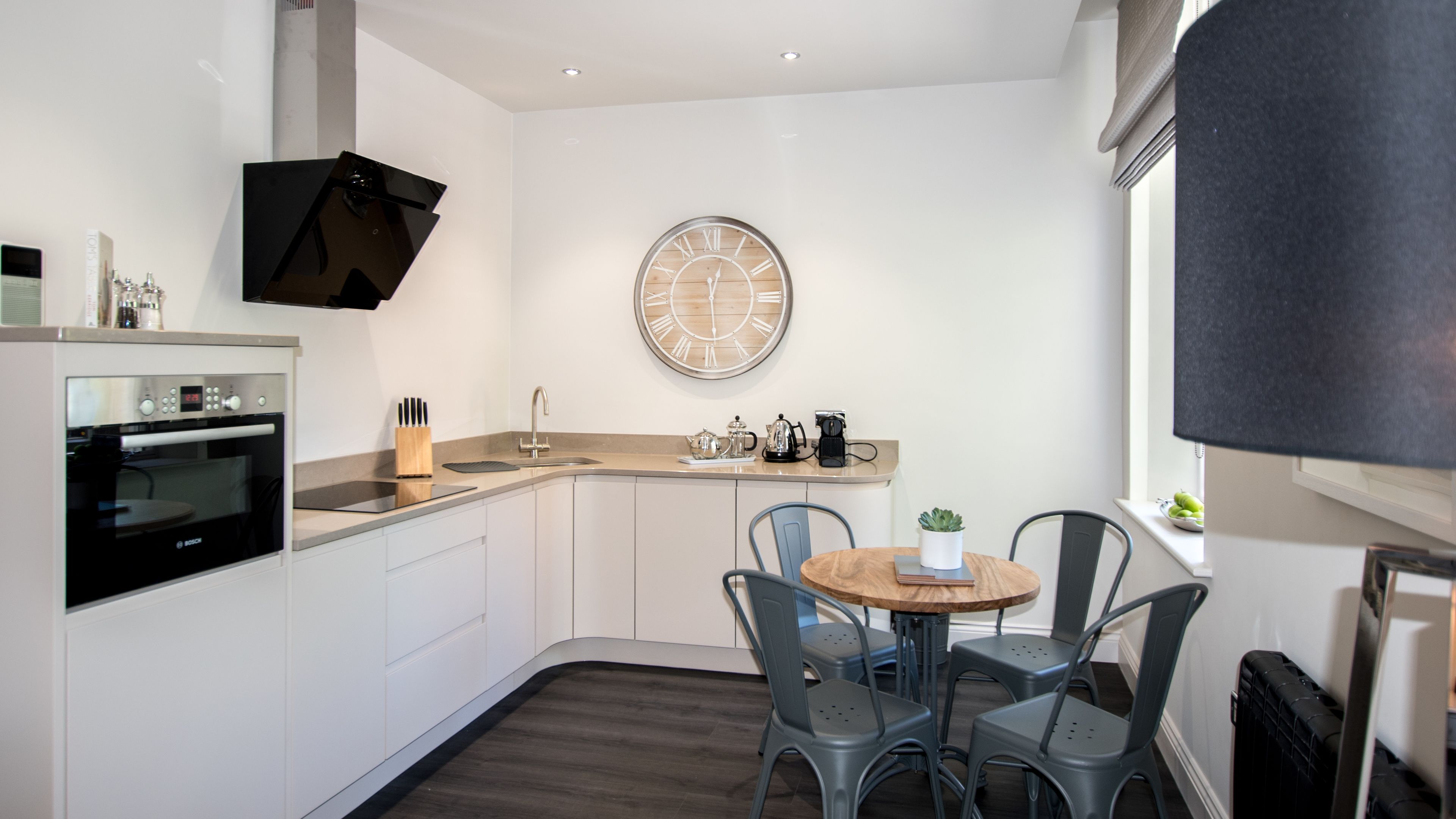A modern kitchen with a Bosch oven, a sink, and a round wooden clock on the wall.