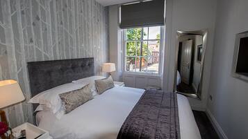 Habitación de hotel con una cama grande, cabecero, dos lámparas de noche, ventana con vistas al exterior y televisor de pantalla plana montado en la pared.
