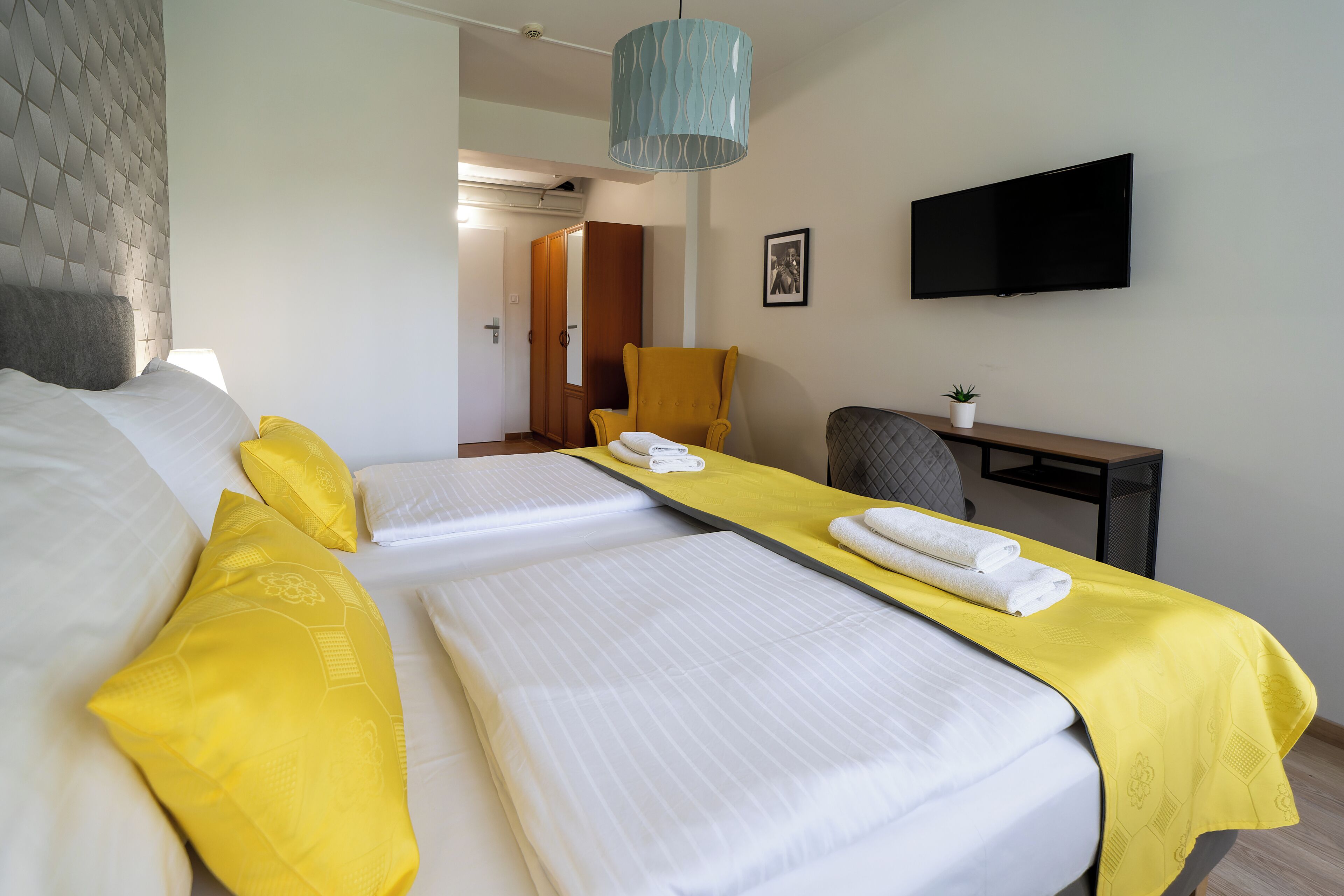 Una habitación de hotel con una cama, un escritorio, una silla, un televisor y una puerta que da a otra habitación.