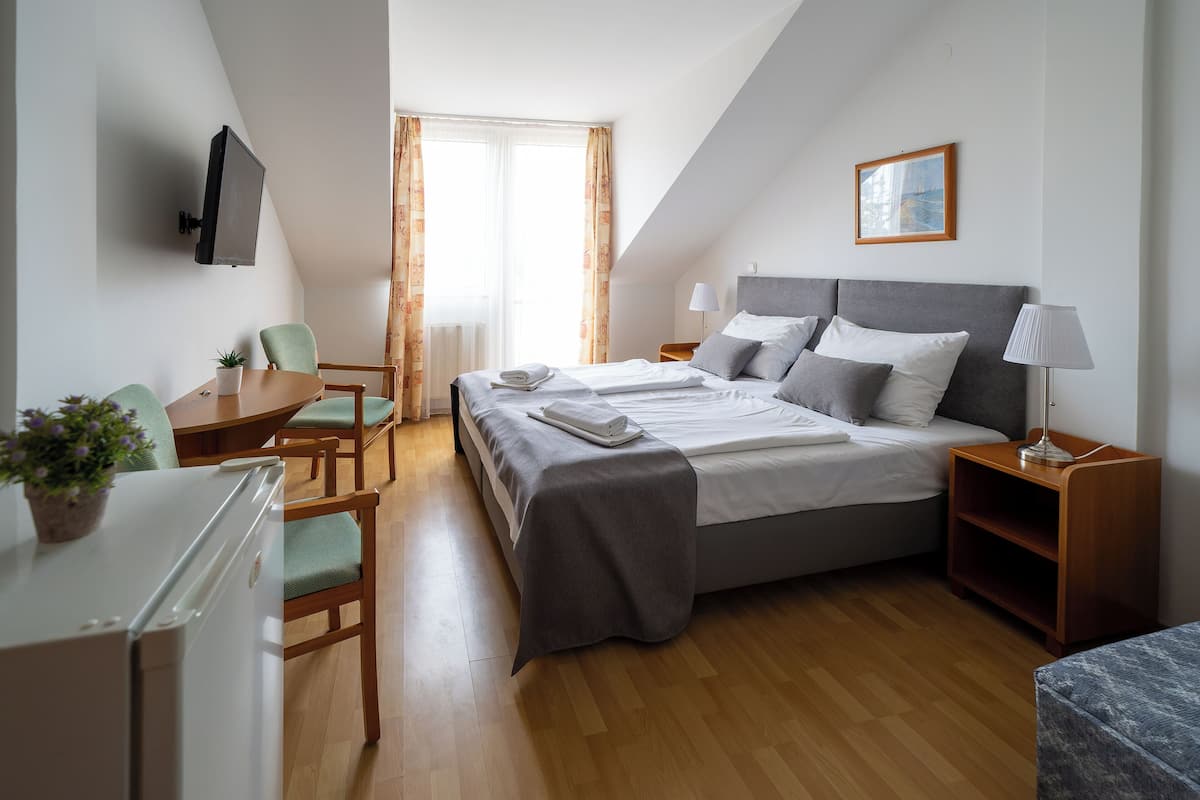 Une chambre d’hôtel comprenant un lit, des tables de chevet, un bureau, une chaise et un téléviseur.