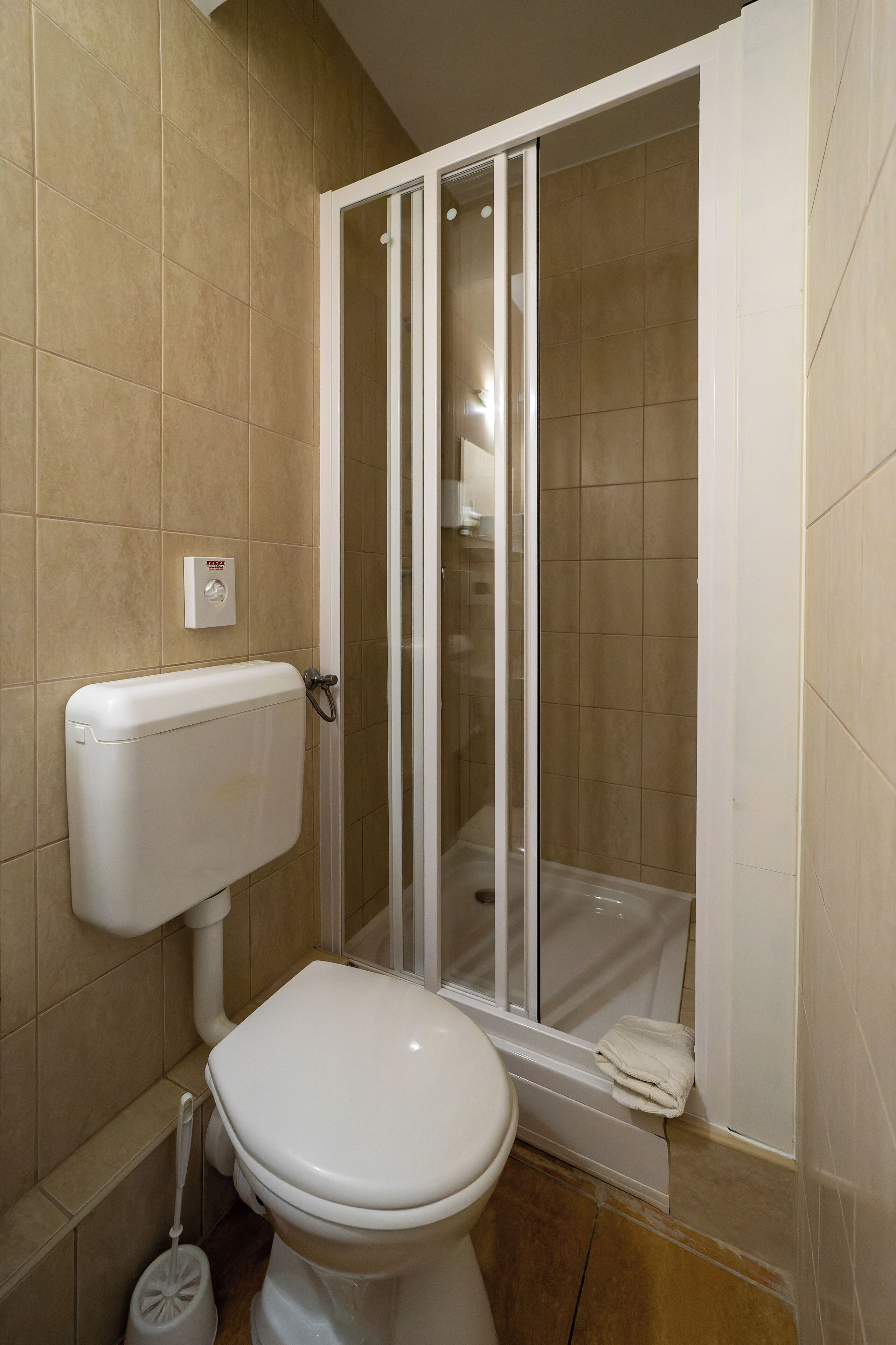 Ein Badezimmer mit Toilette, Duschkabine und Toilettenpapierhalter.