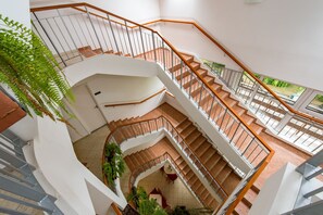 A multi-level indoor staircase with wooden railings and white walls, surrounded by potted plants. - Hotel Forrás Zalakaros (Zalakaros)