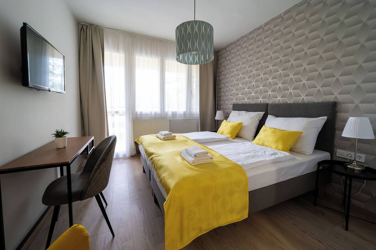 Une chambre d’hôtel avec un lit, un bureau, une chaise, une télévision et une lampe.