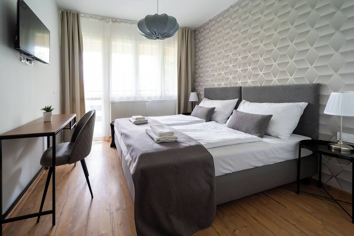 Une chambre d’hôtel moderne équipée d’un lit, de tables de chevet, d’un bureau et d’une chaise.