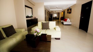 A modern hotel lobby with two sofas, a coffee table, and a vase of flowers. - Hotel Los Almendros (Manta)