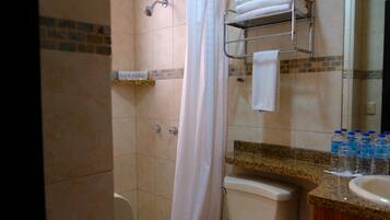 A bathroom with a shower, toilet, and sink. There are towels and toiletries on the counter.