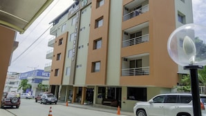A multi-story hotel with balconies, a visible entrance, and a street view with parked cars and traffic cones. - Hotel Los Almendros (Manta)