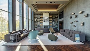 A spacious living area with large windows, a fireplace, and a modern design. - Hotel Geysir (Bláskógabyggd)
