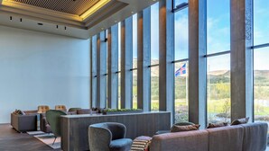 A spacious room with large windows, a modern ceiling design, and a seating area with sofas and chairs. - Hotel Geysir (Bláskógabyggd)