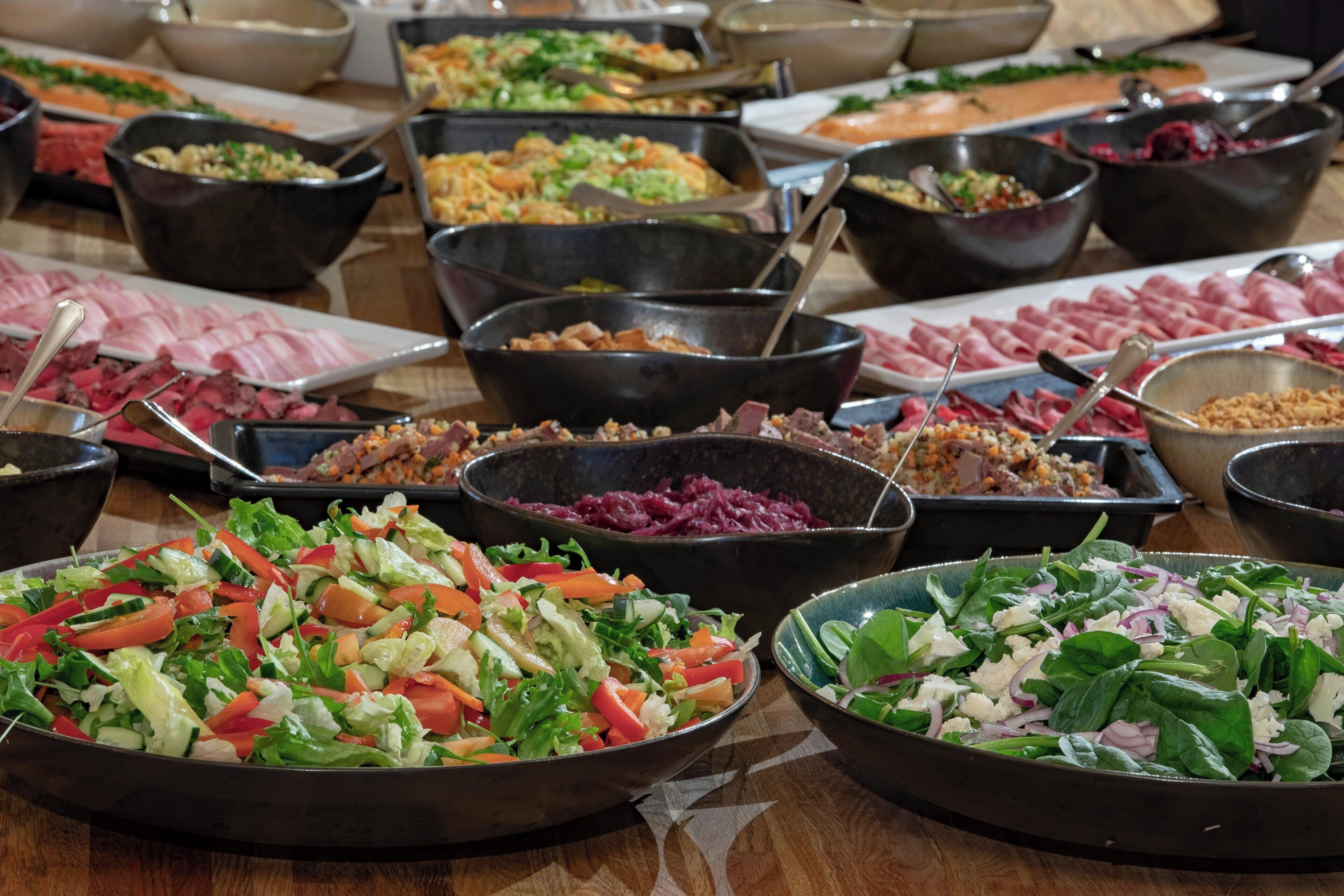 Un bufé con diversos platos, incluyendo ensaladas, carnes y otras preparaciones.