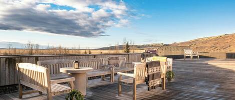 A wooden deck with outdoor seating, a table, and a potted plant.