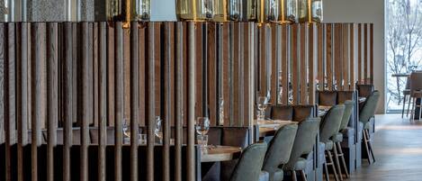 A restaurant with wooden partitions, tables, chairs, and pendant lighting.