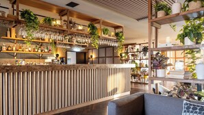 A bar area with shelves of bottles, glasses, and plants. - Hotel Geysir (Bláskógabyggd)
